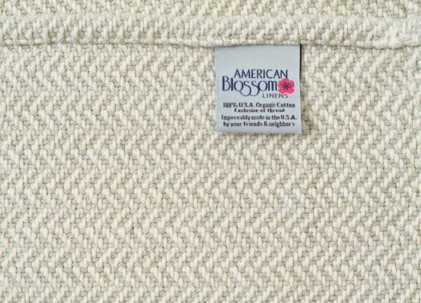 close up of American Blossom herringbone twill weave organic cotton blanket in green.