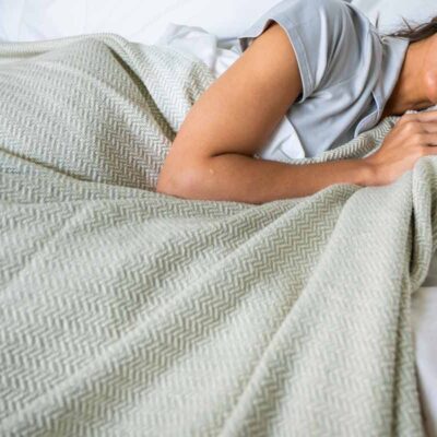 Woman in bed with an Organic Cotton Blanket with Herringbone Weave in Green